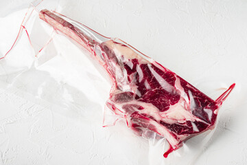 Raw fresh Dry aged raw tomahawk beef steak meat in plastic vacuum package, on white stone ...