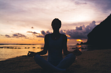 Anonymous woman meditating during sundown - obrazy, fototapety, plakaty