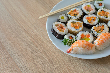 Closeup on sushi set of maki with chopsticks on a white plate