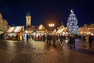 Prague, Czech Republic. Panoramic view of Christmas market at Old Town Square with the city's main Christmas tree in dusk. The Old Town Hall and St. Nicholas Church are visible in the background.