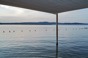 Lake or seaview from the beach, under the parasol, beach umbrella, color illustration photo of tourism.