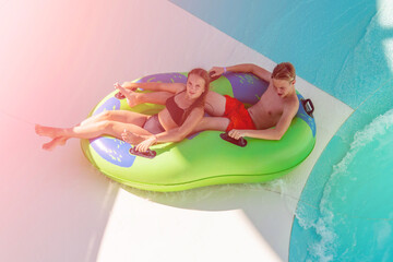 Girl and boy in water Park. Fun on the water. Teen girl and boy having fun in the water slider ....