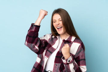 Teenager caucasian girl isolated on blue background celebrating a victory