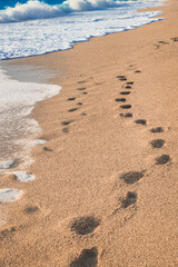 Close-up of blue sea water and send with footprints. Background, copy space