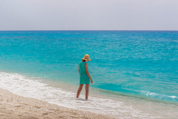 Fototapeta na wymiar Girl in blue dress standing on the beach. Background, copy space