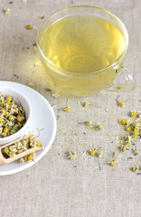Chamomile herbal tea in glass cup and jar with dry herb flowers, above overhead view, naturopathy, natural medicine, healing drinks for sleep, skin and hair care concept