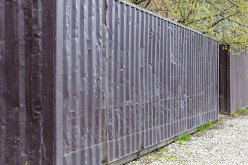 Old 40-foot shipping containers are abandoned and lined up in a street dump during the day