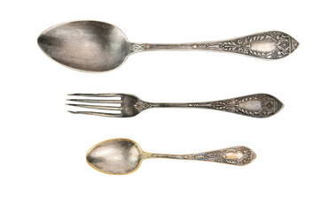 Top view of a tablespoon, fork and teaspoon from one set. The old metal is covered with a dark coating