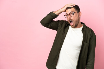 Young Brazilian man isolated on pink background doing surprise gesture while looking to the side