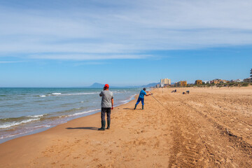 Fisherman throwing the fishing rod, on a beach at sunset, with the Mediterranean sea calm.