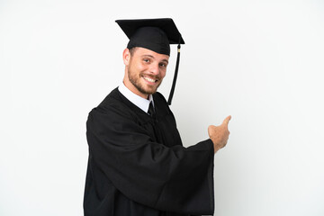 Young university Brazilian graduate isolated on white background pointing back