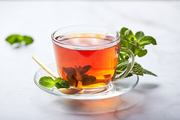 Fototapeta na wymiar Black tea in glass transparent mug with mint leaves. Soothing tea, anti-stress
