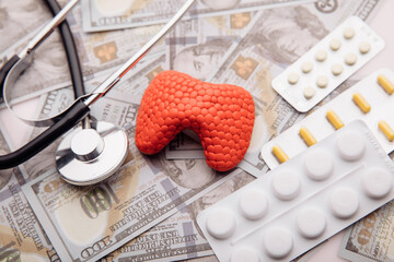 Treatment of diseases of thyroid concept. Model of organ, pills and money close-up