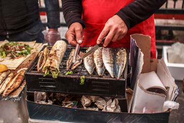 Balik ekmek. Cooking grilled mackerel fish in lavash with vegetables and sauce. Traditional Turkish street food