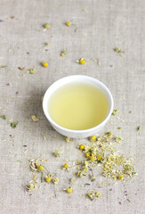 Chamomile herbal tea in chinese cup and dry herb flowers, above overhead view, naturopathy, natural medicine, healing drinks for sleep, skin and hair care concept
