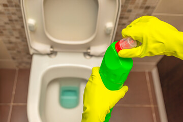 Toilet cleaners. Liquid bottle. Top view of the toilet. Open the bottle of toilet cleaner by hand.