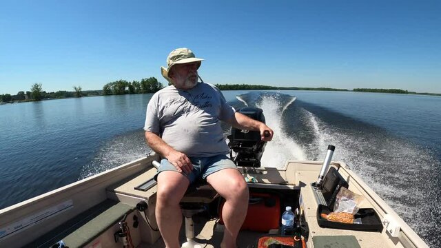 old man driving fishing boat fast sunny day