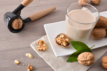 Glass full of vegetable milk and walnut on table elevated
