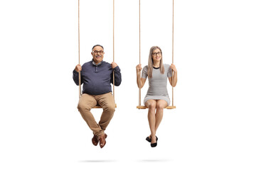 Mature man and a young woman sitting on swings and looking at camera