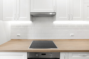 White kitchen with wooden countertop with induction cooktop