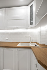 Fototapeta na wymiar White kitchen with wooden countertop with faucet and sink