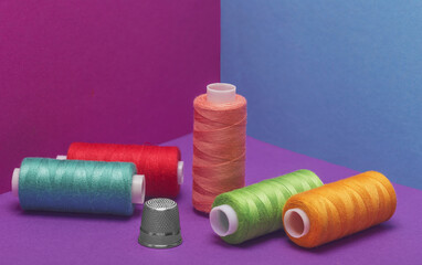  Colored threads on a bobbin on a colored background.