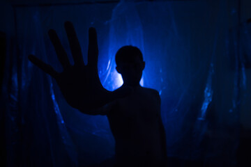 A man in the dark in a blue light. Silhouette of a man in the dark.