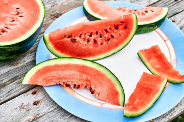 Slices of ripe fresh watermelon on wooden table outdoor. Healthy eating summertime concept. Organic fruits.