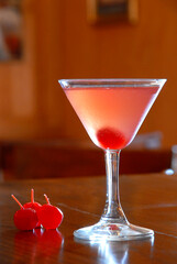 Cocktail with cherry, fresh cocktail in a glass on the wooden bar and cherries as decoration, with a warm atmosphere