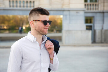 Un jeune homme la veste sur l'épaule au printemps