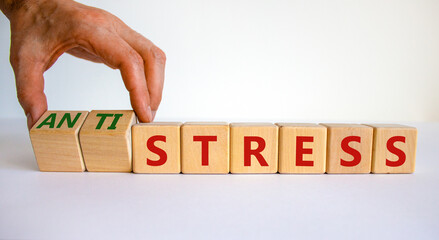 Antistress vs stress symbol. Doctor turns cubes and changes the word stress to anti stress. Beautiful white table, white background. Medical, psychological, antistress vs stress concept. Copy space.