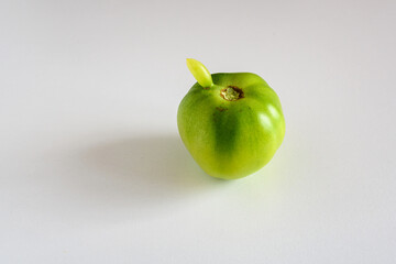 Green tomato with the protruding part of the second tomato.