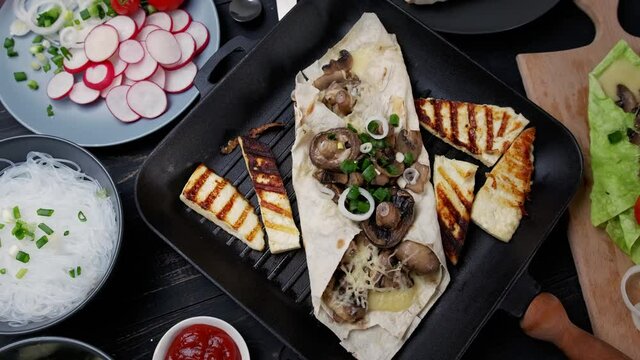 Assortment of street food on a dark wood table. mushrooms, shawarma, Adyghe cheese, herbs, noodles. Served on fried bread
