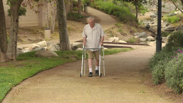 Senior man (82 year old Caucasian) walking in the park using a walker