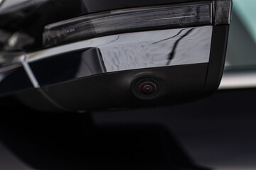 Close up view of surround view camera system on modern car side rear mirror. Blind spot and parking assistant camera.