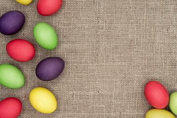 Background with multicolored easter eggs on a jute sacking.