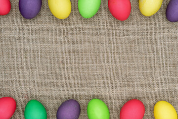 Multicolored Easter eggs on a burlap background. Easter frame.