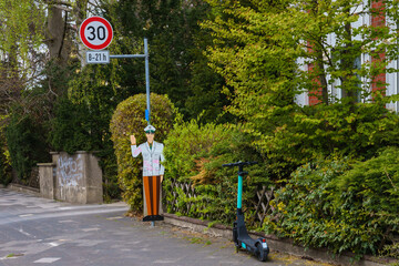 A mock-up of a police officer warns of a speed limit. Electric scooter in the foreground.