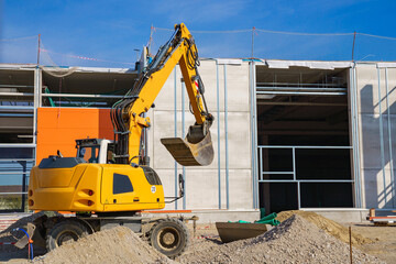 Yellow excavator on the background of a building under construction.