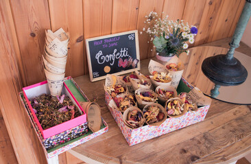 Rose petal confetti cones and sign on display on a table at a wedding