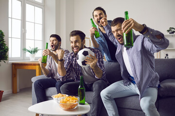 Cheering TV soccer fans with chips snack, beer watching match at home. Excited man friends loudly...