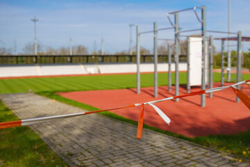 Red and white barrier warning tape prohibiting entry to the sports stadium. Selective focus.