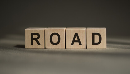 A wooden blocks with the word ROAD written on it on a gray background.