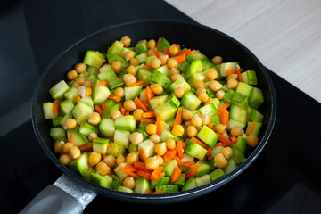 Stewed vegetables with chickpeas, zucchini and carrot in frying pan. Easy vegan recipe, healthy nutrition or clean eating. Healthy food concept. Selective focus.