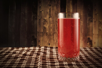 The glass of red berry juice on rustic wooden background.