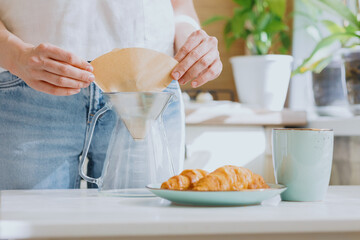 European woman brews coffee at home in her kitchen and enjoys her morning, good morning, caucasian woman makes coffee filter at home and enjoys her day off, woman does internet detox on her day off