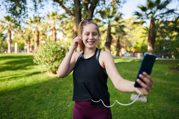 a beautiful red-haired girl with green eyes in a medium shot stretches her muscles to be able to start playing a sport in a park in the center of the city