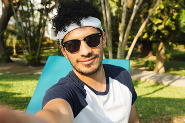 Selfie of Young Hispanic man on vacation relaxing by the pool - young man taking a selfie while spending time relaxing