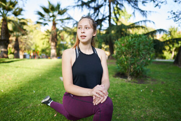 a beautiful red-haired girl with green eyes in a whole shot takes a medication in the middle of a park in the center of the city