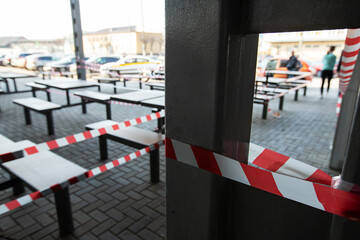 the summer cafe of the fast food restaurant is closed for quarantine during the coronavirus epidemic, access to visitors is prohibited, and chairs and tables are tied with a warning tape